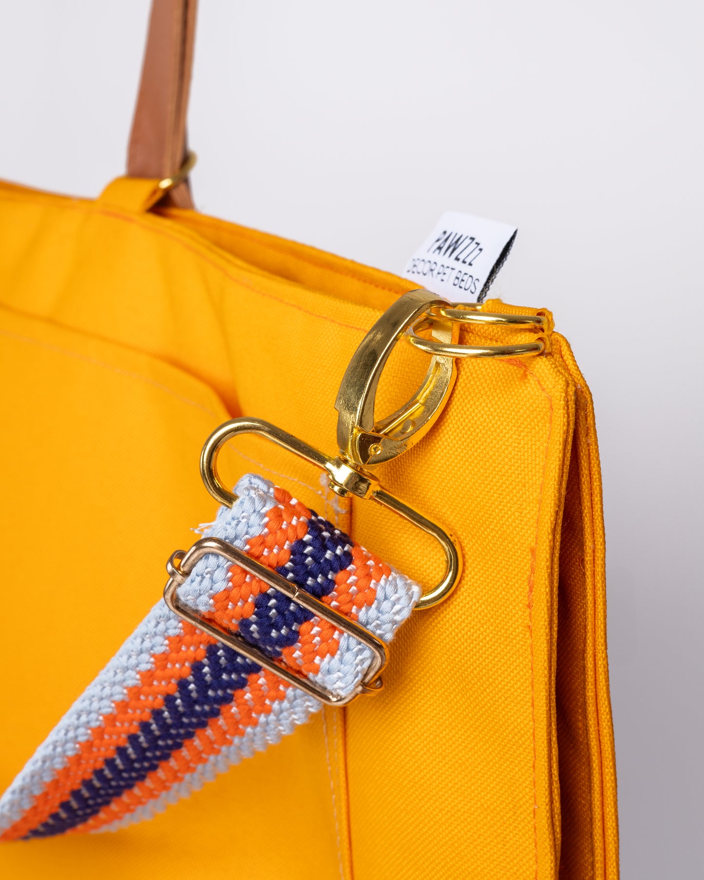 Detalhe da manta de viagem Cosmopolitan laranja com mosquetao e alça colorida