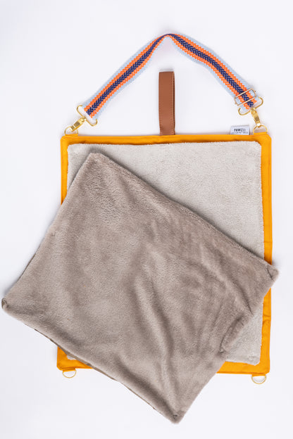Detalhe da manta de viagem Cosmopolitan laranja com as três opções de topo intercambiáveis: impermeável, pelo macio e toalha absorvente.